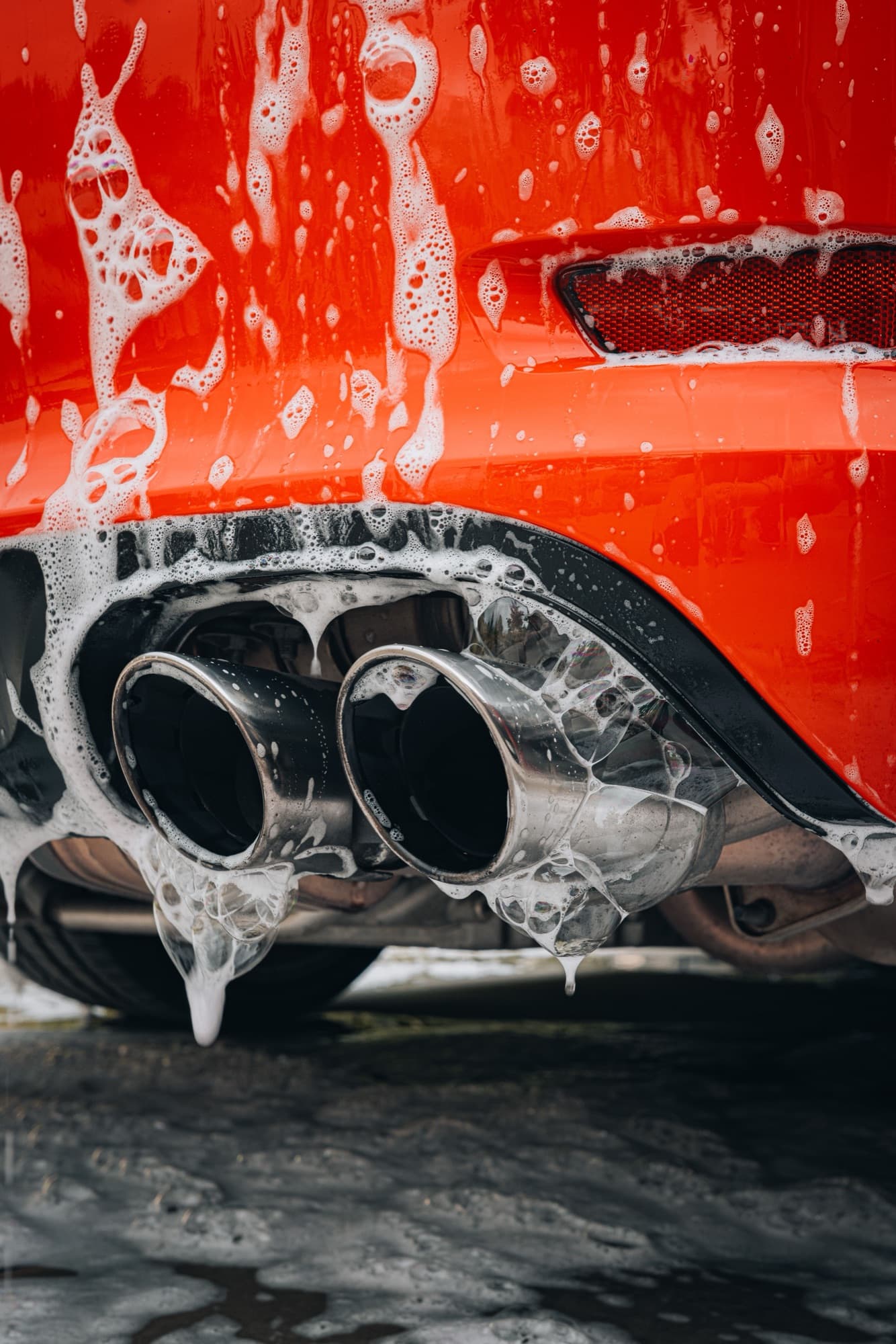 Thick foam dripping from a pair of exhaust tips during a hand wash