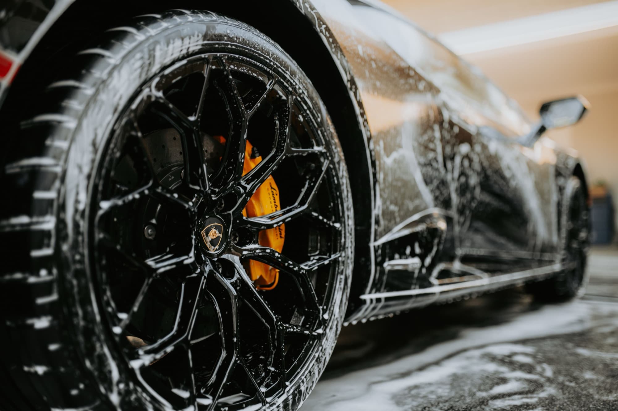Foam-covered wheel and rocker panel on a sports car in golden light